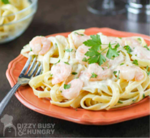 A plate of creamy fettuccine Alfredo garnished with fresh parsley and grated Parmesan cheese.